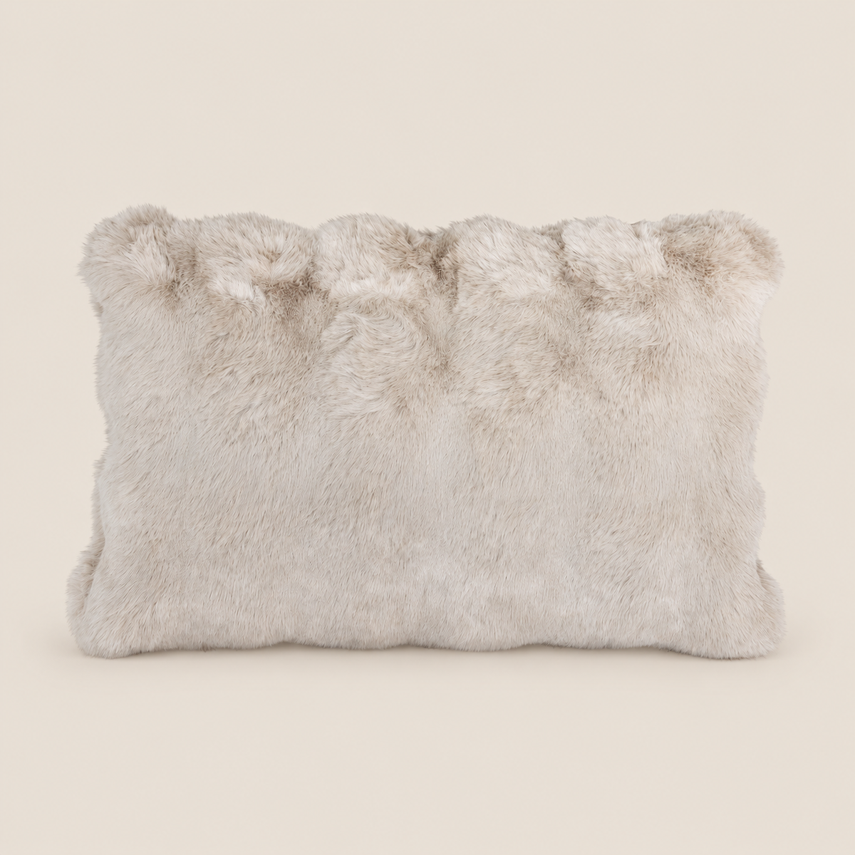 Kunstfellkissen LUCI Beige 50 × 35 cm vor warmem beigem Hintergrund