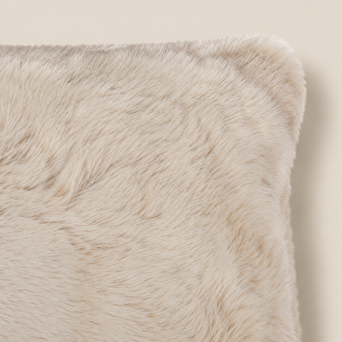 SUSAN Kunstfellkissen Beige 50 × 35 cm – Nahaufnahme auf beigem Hintergrund