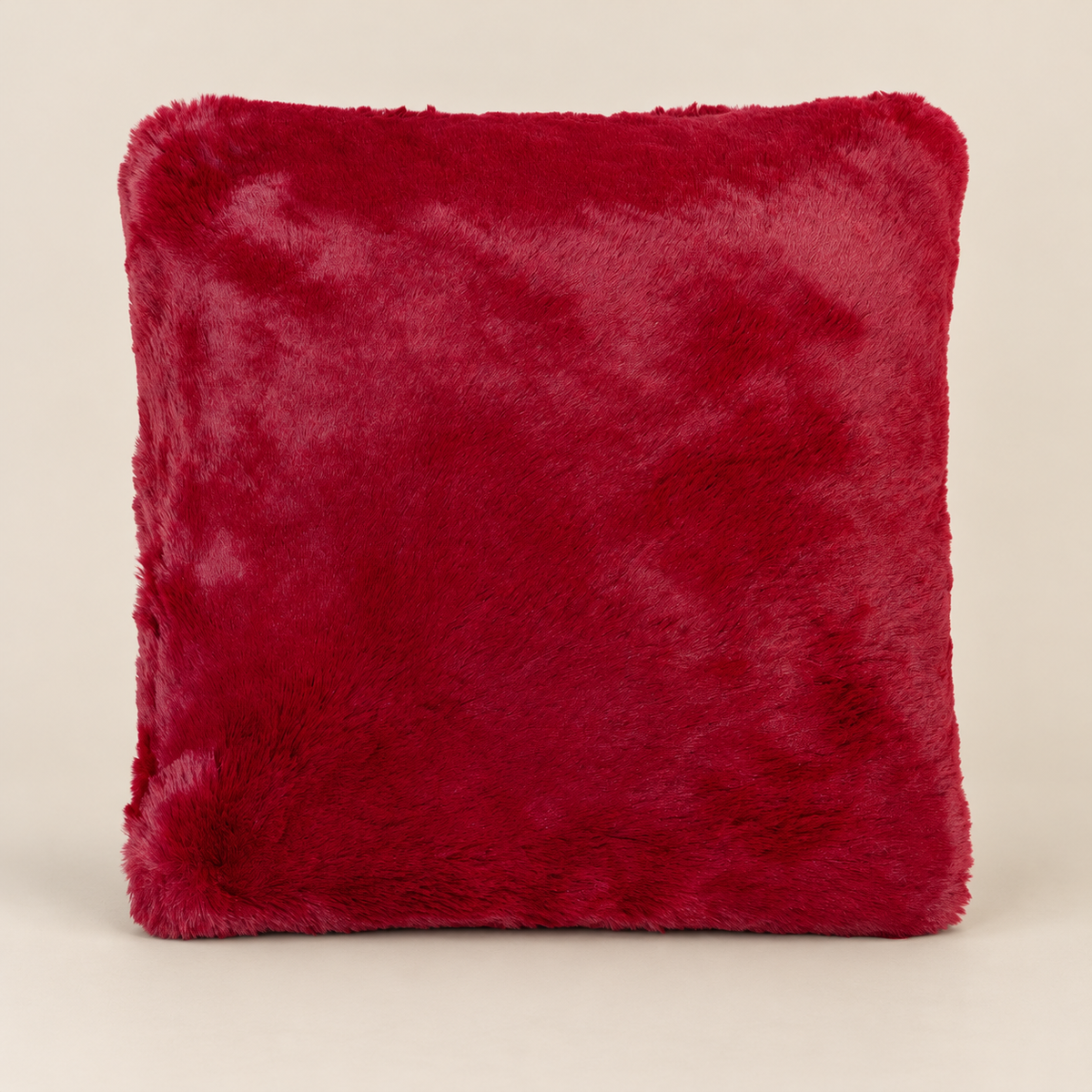 SUSAN Kunstfellkissen Burgundy 50 × 50 cm – Produktansicht auf warmem beigem Hintergrund